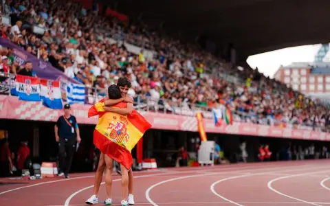 Dos atletas se abrazan con la bandera de España en el campeonato Europa sub 20 atletismo.