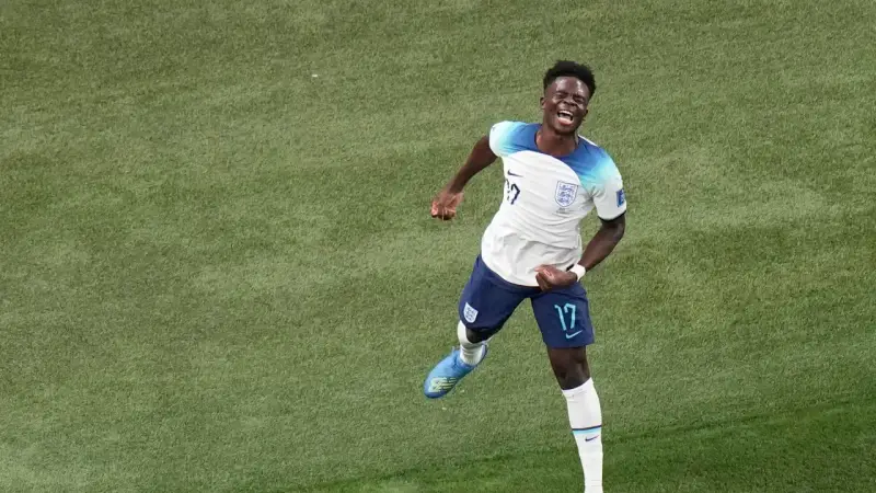 Bukayo Saka celebra un gol con euforia en el campo de fútbol.
