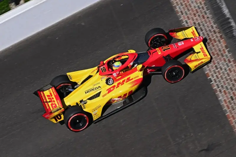 Alex Palou, piloto del coche número 10, acelera en la pista con su monoplaza amarillo y rojo de DHL.