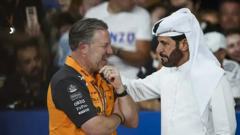 Mohammed Ben Sulayem, con túnica blanca, conversa animadamente con un hombre con polo naranja de McLaren.